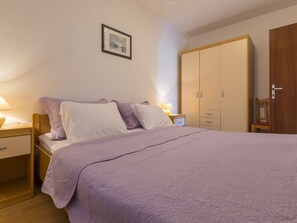 Un dormitorio con cama, mesitas de noche, armario y un cuadro en la pared.