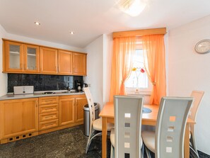 Een compacte keuken met houten kastjes, een koffiezetapparaat en een eethoek met een tafel en stoelen.