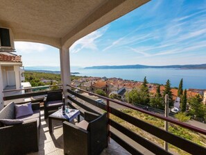 A balcony with wicker furniture, a view of a lake, and a town in the background. - Stupar 2 / HR-09721-02 by Interhome (Crikvenica)