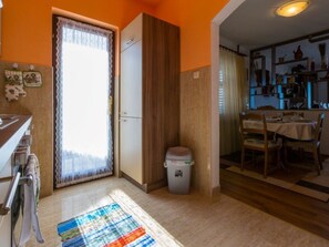 A kitchen with a window, a trash bin, and a dining area with a table and chairs. - Stupar 2 / HR-09721-02 by Interhome (Crikvenica)