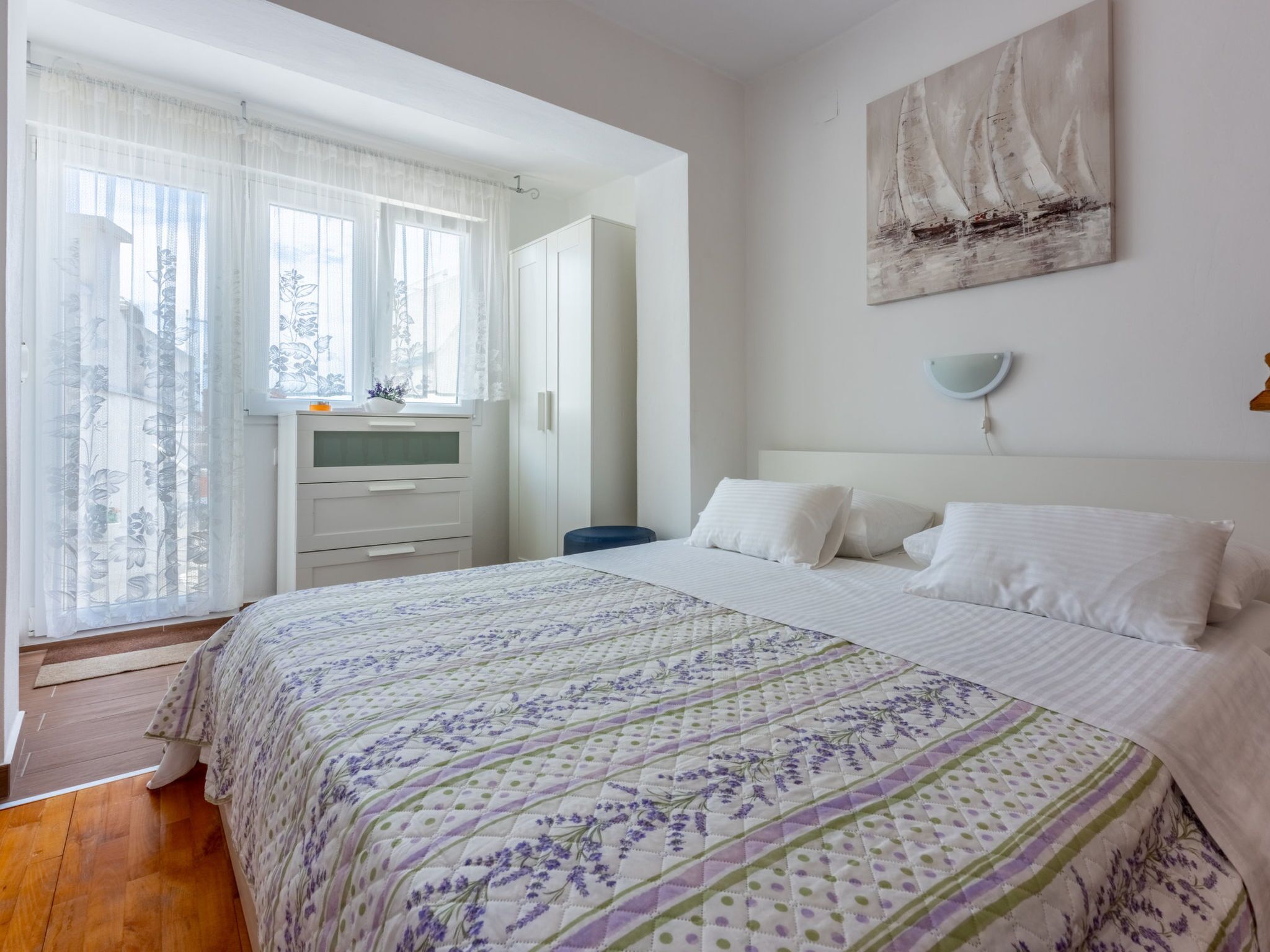 A bedroom with a bed, a dresser, a mirror, and a painting on the wall.