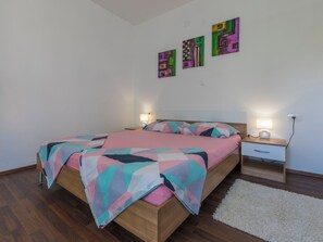 A bedroom with a bed, nightstands, a rug, and abstract wall art. - LUKA plavi 2 / HR-10238-02 by Interhome (Crikvenica)