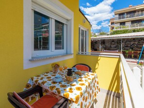 A yellow building with a balcony table set for breakfast. - LUKA plavi 2 / HR-10238-02 by Interhome (Crikvenica)