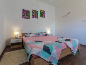 Ein Schlafzimmer mit einem Bett, zwei Nachttischen, einem Teppich und drei Wandbildern.