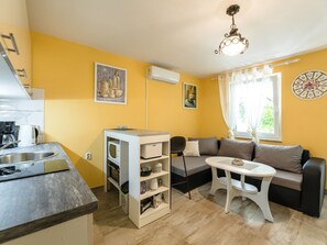 A compact living space with a kitchenette, a sofa, a small table, and a clock on the wall. - Palatino / HR-10637-01 by Interhome (Crikvenica)
