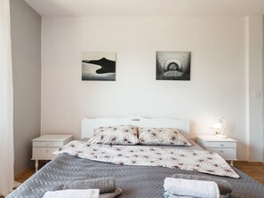 A bedroom with a bed, two nightstands, a lamp, and two wall art pieces. - Palatino / HR-10637-01 by Interhome (Crikvenica)
