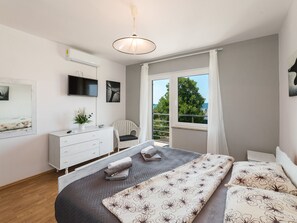 Ein Schlafzimmer mit Bett, Schminktisch, Stuhl, Fernseher und Fenster mit Blick.