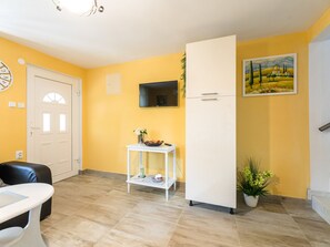 A room with a white door, a white table, a white cabinet, a flat-screen TV mounted on the wall, and a painting. - Palatino / HR-10637-01 by Interhome (Crikvenica)