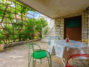 Eine Terrasse im Freien mit Tisch, Stühlen und einer Treppe zu einem Eingang mit Steinmauer.