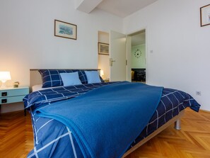 A bedroom with a bed, a nightstand, a lamp, and a door leading to another room. - VESNA / HR-08535-01 by Interhome (Crikvenica)
