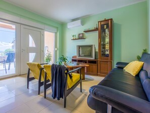 A living room with a sofa, a TV, and a dining area with chairs and a table. - VESNA / HR-08535-01 by Interhome (Crikvenica)