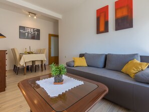 Ein modernes Wohnzimmer mit einer Couch, einem Esstisch und einem Couchtisch mit Pflanze.