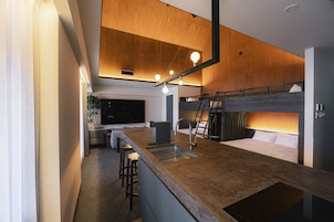 A modern kitchen with a wooden countertop, bar stools, and a built-in stove.