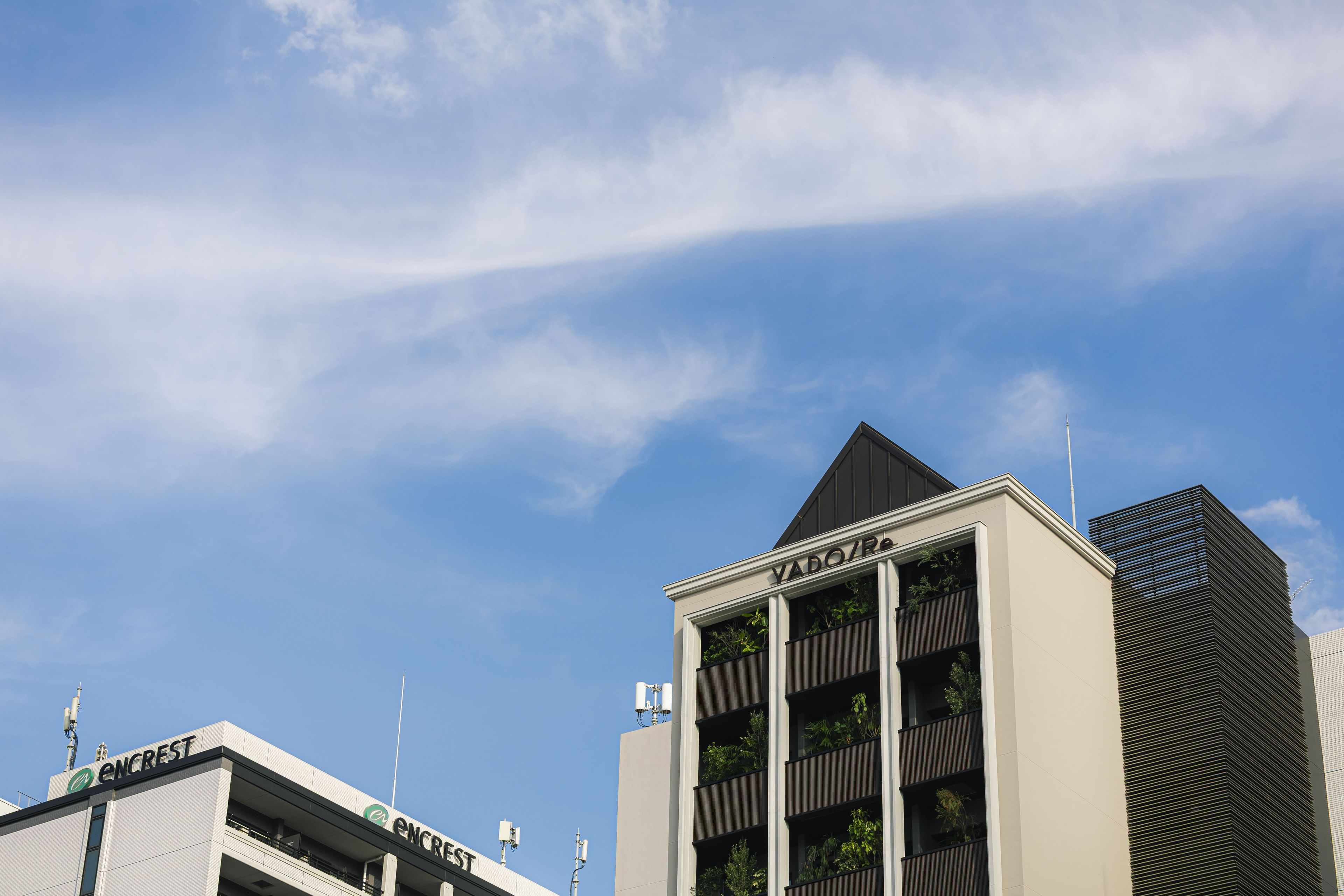 A modern building with a prominent ENCREST sign, a triangular roof, and a tall antenna.