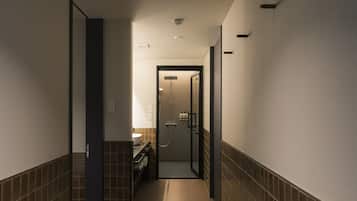 A narrow hallway with a bathroom at the end featuring a glass-enclosed shower and a toilet.