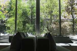A room with a large window, a bed with pillows, and a view of greenery outside.