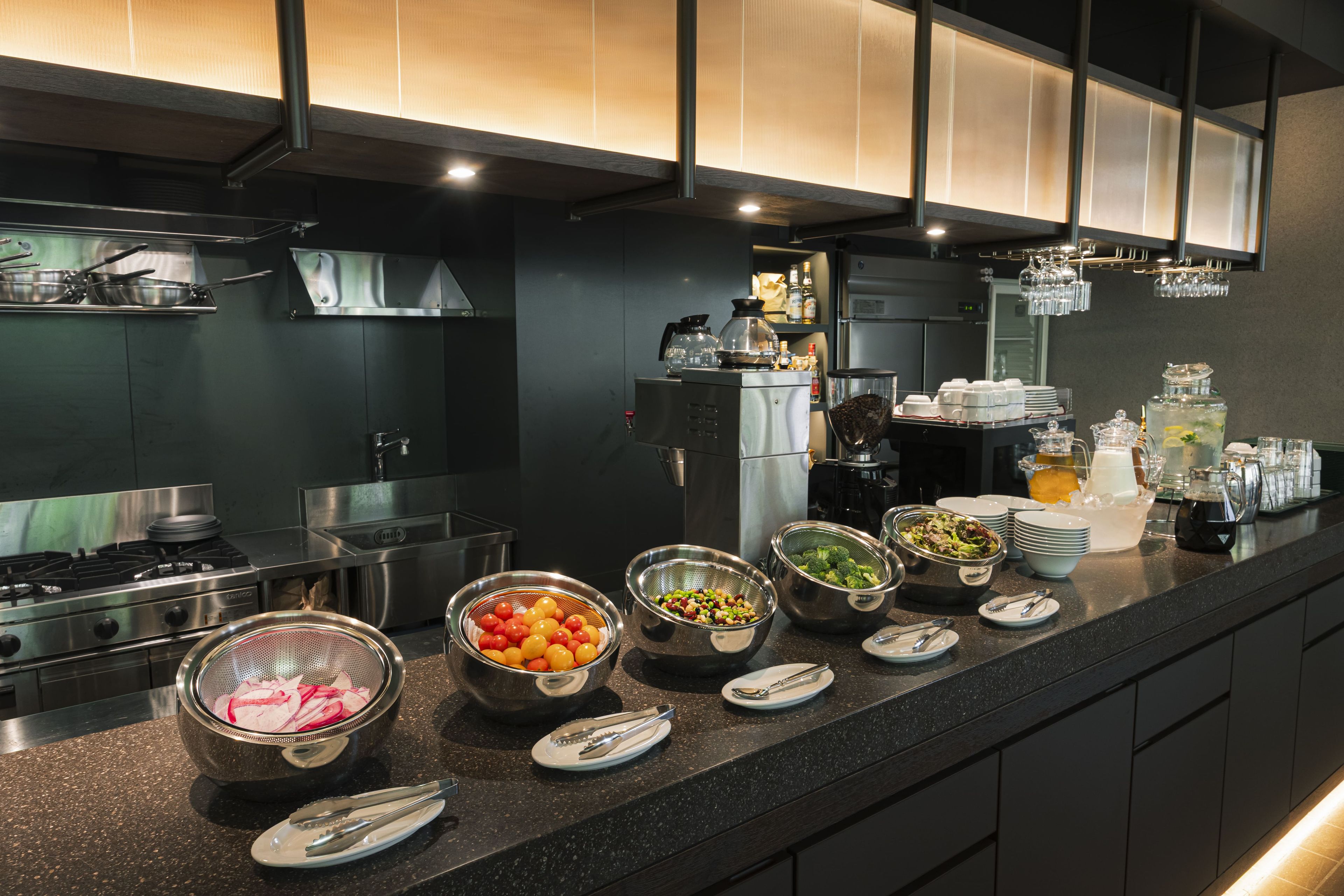 A modern kitchen with stainless steel appliances, a variety of food items on the counter, and a bar area with glasses and bottles.