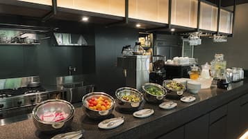 A modern kitchen with stainless steel appliances, a variety of food items on the counter, and a bar area with glasses and bottles.