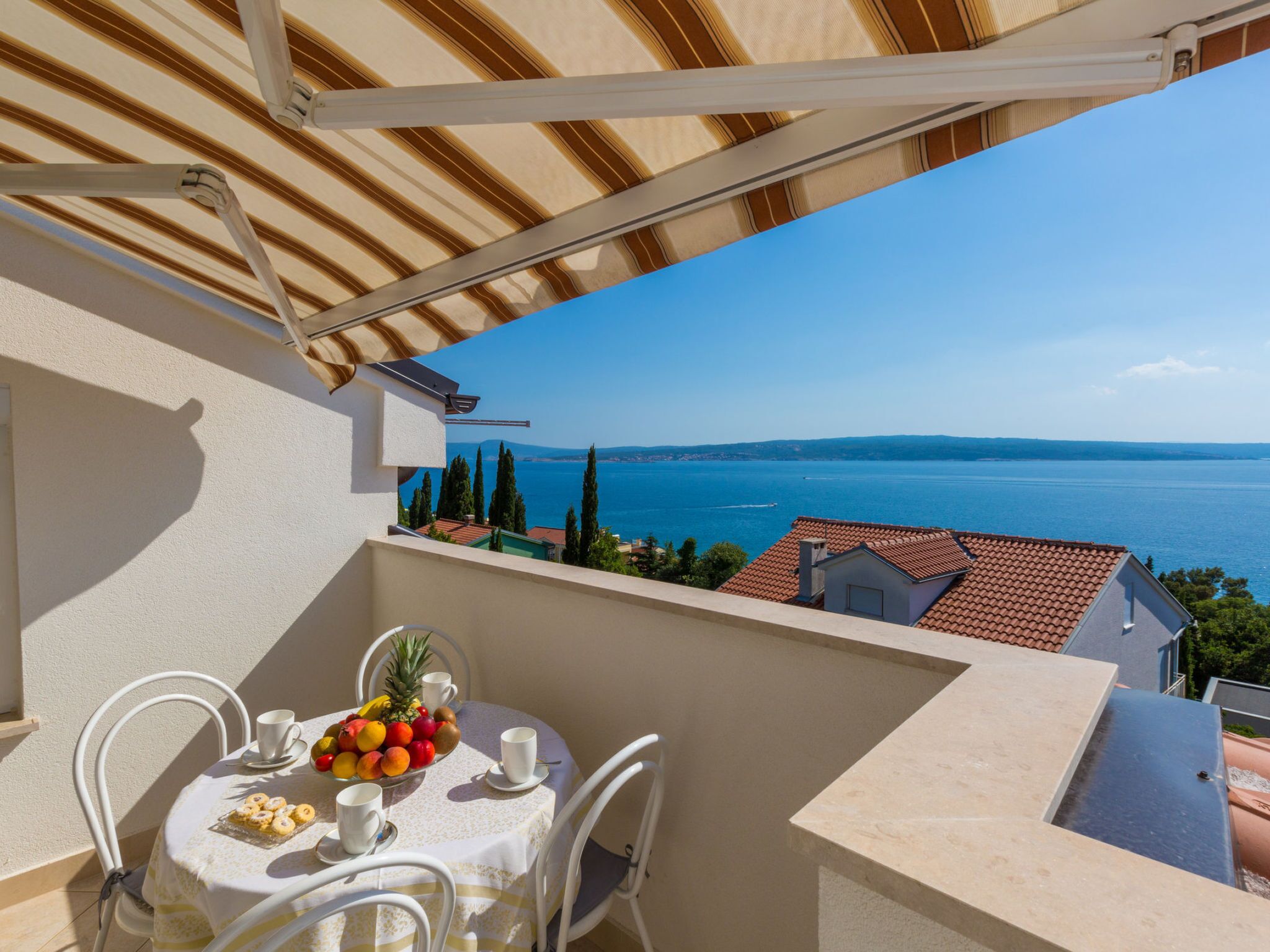 Un balcon avec une table dressée pour deux personnes, offrant une vue sur la mer.