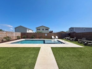 A backyard with a swimming pool, a grassy lawn, and a wooden fence. - Salty Breeze, 5 bed/4.5 bath POOL (Surf Cithh)
