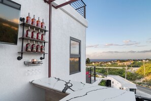 Un bâtiment moderne à l’extérieur blanc, doté d’un balcon avec une balustrade et offrant une vue sur un paysage côtier.