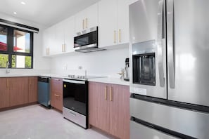 A modern kitchen with stainless steel appliances, wooden cabinets, and a dishwasher. - Luxe Loft Penthouse, a luxury property in Montego Bay, 6 mins from MBJ airport (Montego Bay)