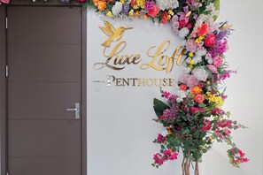 Un mur orné d’une composition florale et sur lequel on peut lire le texte : « Luxe Loft Penthouse ».