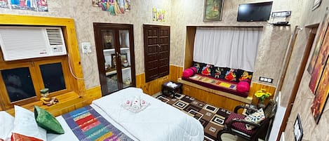 A room with a bed, a sofa, a television, and artwork on the walls.