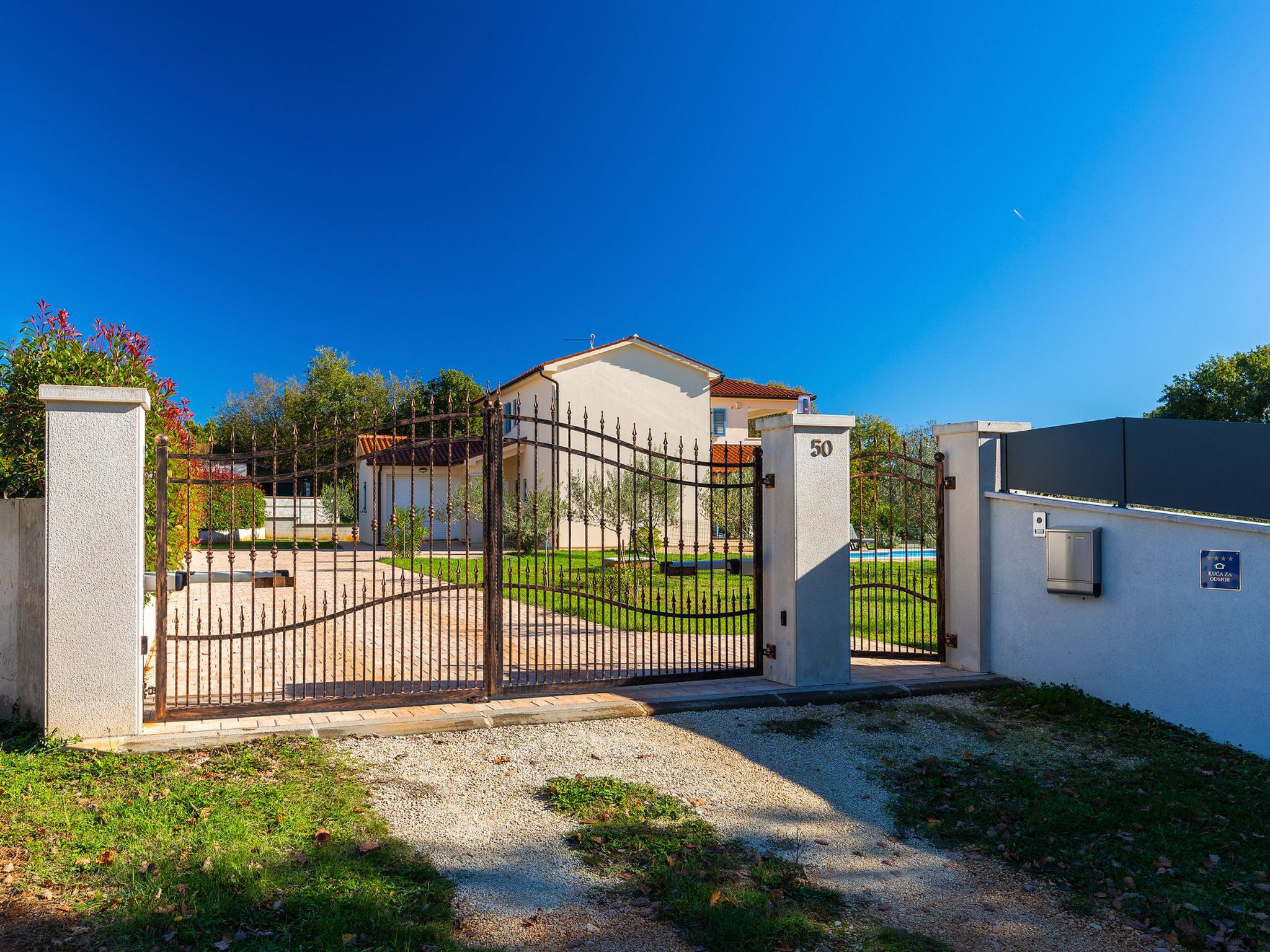 A gated residential area with a house, a number 50 sign, and a pool.