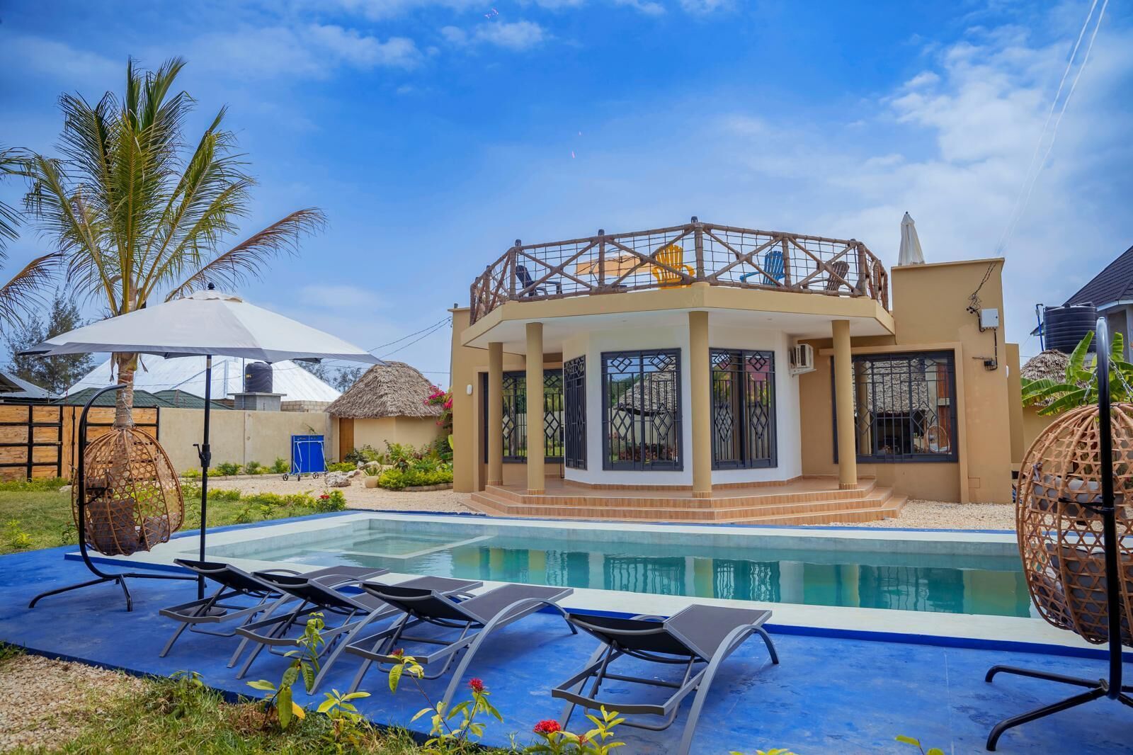 A poolside area with lounge chairs, a covered seating area, and a pool.