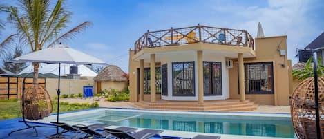 A poolside area with lounge chairs, a covered seating area, and a pool.