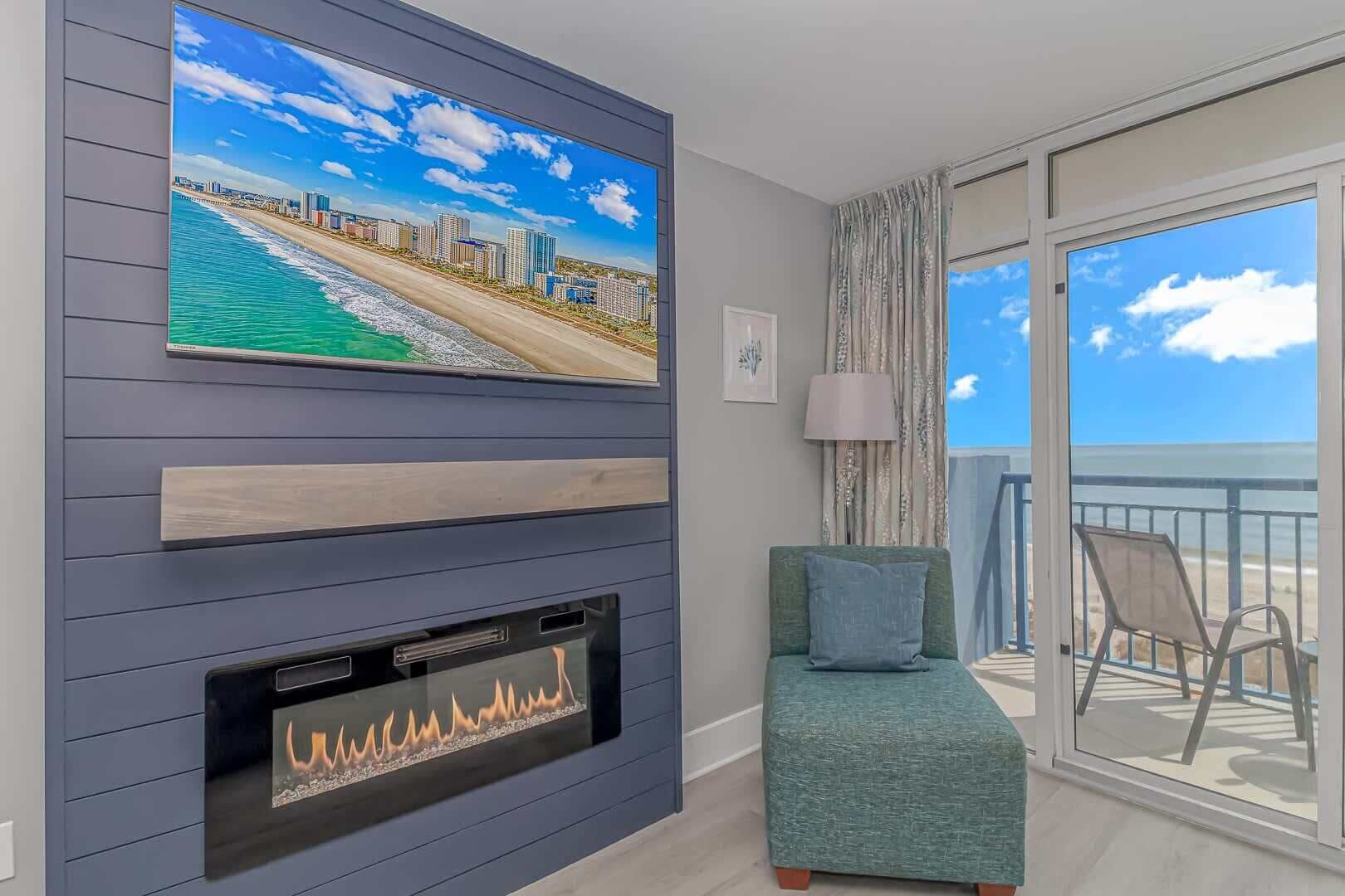 Un salon moderne doté d’un grand téléviseur, d’une cheminée et d’un balcon offrant une vue sur la plage et le paysage urbain.