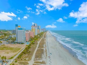 A coastal cityscape with a long beach, high-rise buildings, and a clear blue sky. - Atlantica 452 Oceanfront Escape (Myrtle Beach)