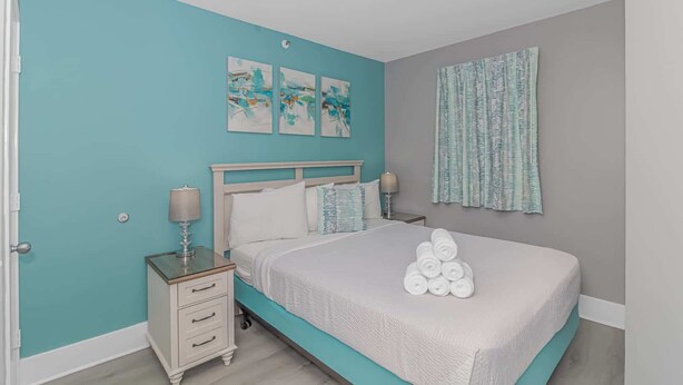 A bedroom with a bed, nightstands, a window with curtains, and artwork on the wall. - Atlantica 452 Oceanfront Escape (Myrtle Beach)