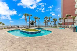 A pool area with multiple swimming pools, palm trees, and a building in the background. - Atlantica 452 Oceanfront Escape (Myrtle Beach)