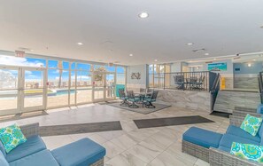 A hotel lobby with a pool view, outdoor seating, and a staircase. - Atlantica 452 Oceanfront Escape (Myrtle Beach)