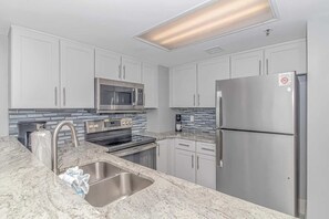 A modern kitchen with stainless steel appliances, a built-in oven, and a microwave. - Atlantica 452 Oceanfront Escape (Myrtle Beach)