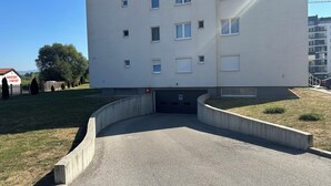 A multi-story building with a flat facade, several windows, and a parking area in front. - Ados Apartment • Stunning Views • 3BR • Free Garage (Ilidža)