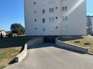 Un edificio de varios pisos con fachada plana, varias ventanas y un estacionamiento al frente.