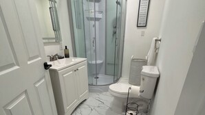 Een badkamer met een douchecabine, toilet en een wastafel met spiegel.
