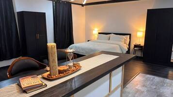 A hotel room with a bed, bedside lamps, a desk with a chair, and a large window.