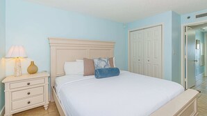 A bedroom with a bed, nightstand, lamp, and a door. - Atlantica 200 Oceanfront Condo (Myrtle Beach)
