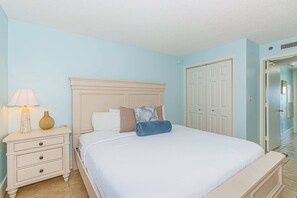 Ein Schlafzimmer mit Bett, Nachttisch, Lampe und einer Tür.