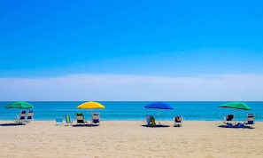 Ein Strand mit mehreren Liegestühlen und Sonnenschirmen.