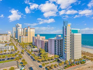 Eine Küstenstadt mit Hochhäusern, blauem Himmel und einem Strand im Hintergrund.