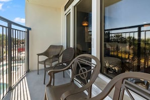 Ein Balkon mit Korbstühlen, einer Glastür und Blick auf Palmen.