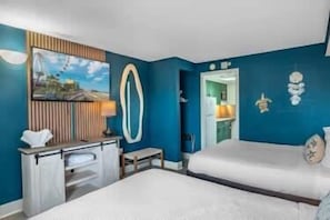 A hotel room with a bed, a desk, a mirror, and a wall with a circular decoration. - Boardwalk 135 Oceanfront Getaway (Myrtle Beach)