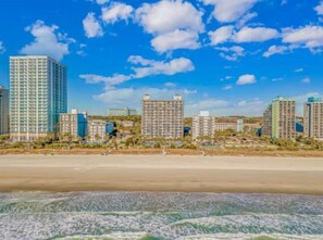 Eine Küstenstadt mit hohen Gebäuden, einem Sandstrand und blauem Himmel.