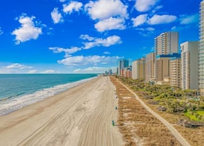 A beach with a clear sky and buildings along the shore. - Boardwalk 135 Oceanfront Getaway (Myrtle Beach)