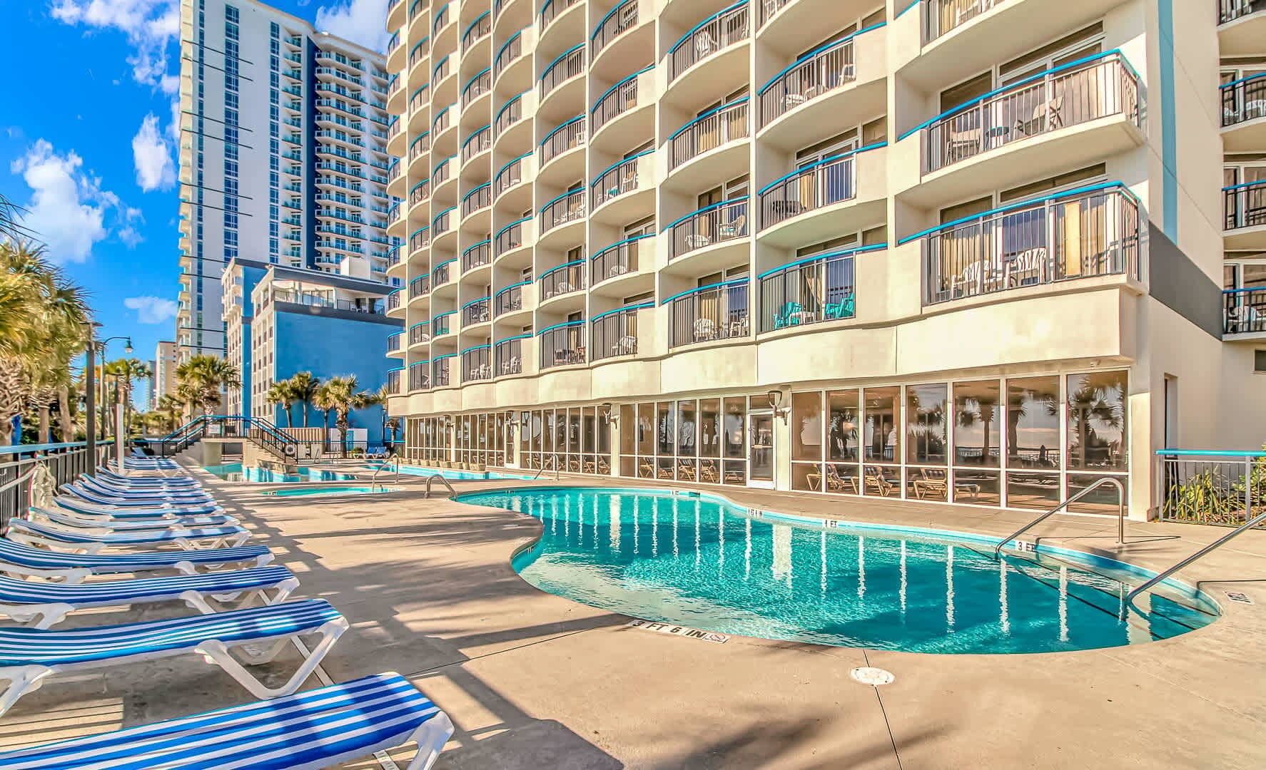 Un hôtel doté d’une piscine, de plusieurs balcons et offrant une vue sur les palmiers.